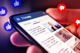 A hand holds a phone that is on a generic “News” site. Blue thumbs-up and red thumbs-down icons float above.