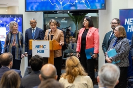 Maura Healey speaks at a lecturen while Sally Kornbluth, Dev Shenoy, Kim Driscoll, Ben Linville-Engler, and Carolyn Kirk stand alongside her on a small stage in front of a seated audience