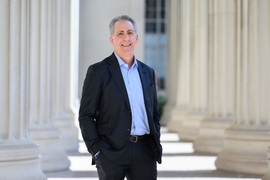 Ian Waitz stands outside for a portrait. The columns of Building 10 are in the background.