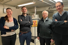 Jennifer Rupp, Thomas Defferriere, Harry Tuller, and Ju Li pose standing in a lab, with a nuclear radiation warning sign in the background