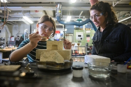 Rhea Vedro supervises a student working with metalsmithing tools