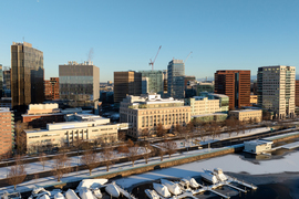 Snowy aerial view of MIT buildings including MIT Sloan, Memorial Drive, and icy river.