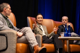 Lucia Tian sits between two others on a stage and is speaking.