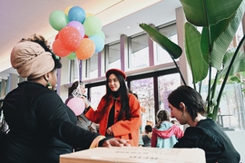 Two women talking, one holding a bunch of colorful balloons