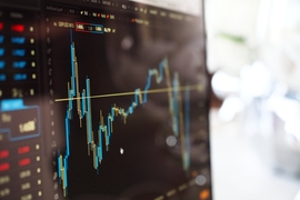 Photo of a line graph on a computer screen, representing data analysis being performed in an office-like setting.