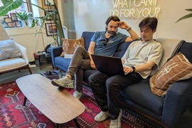 Alex Shalek and Bokai Zhu look at a laptop while sitting on a sofa in an office.