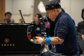 Profile view of Jose Ramos Santana, covered with sensors, playing a piano