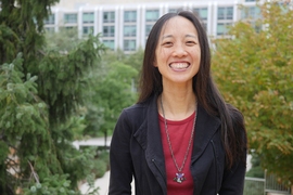 Vanessa Cheung poses outside with trees and a lab building in the background
