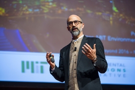 John Fernandez gesturing with his hands as he gives a presentation.