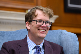 Hank Green smiles and sits in chair