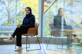 Sarah Alnegheimish sits in front of a wall of windows overlooking out-of-focus trees