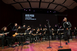 Lupe Fiasco performs with the MIT Festival Jazz Ensemble on an indoor stage