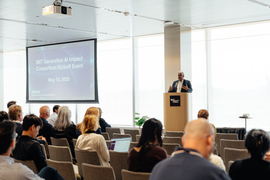 Anantha Chandrakasan stands at a lectern in front of rows of people in chairs. A slide behind him reads MIT Generative AI Impact Consortium Kickoff Event.