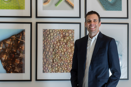 John Hart poses in front of some framed photomicrograph art