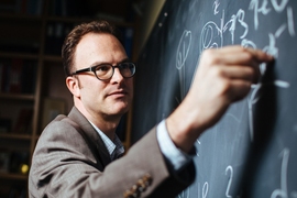 Jesse Thaler writes on a chalkboard