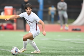 Dilin Meloni running on the field, about to kick a soccer ball