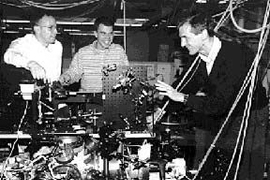 Michael Andrews, Marc-Oliver Mewes, and Wolfgang Ketterle gather around the machine they and their MIT collaborators used to demonstrate the first atom laser. Mr. Andrews and Mr. Mewes are graduate students in physics; Dr. Ketterle is an assistant professor in the department.