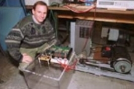 Research scientist David Perreault kneels next to an alternator that could dramatically increase the power available to future cars. The laboratory-scale apparatus nearest Dr. Perreault contains the new switches that enable this increase; the other part of the alternator is at right.