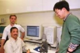 James Biggs, postdoctoral associate in the Research Lab of Electronics (left), Professor Mandayam Srinivasan, director of MIT's Touch Lab, and mechanical engineering graduate student Jung Kim observe the movement of a robotic arm driven by signals from a monkey at Duke University.