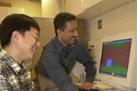 Mechanical engineering graduate student Jung Kim operates the phantom to touch a colleague in London as senior research scientist Mandayam A. Srinivasan watches on-screen representations of each touch.