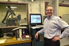 Professor John B. Heywood relaxes in the Sloan Automotive Laboratory, which includes a test cell (background) containing a 2002 Cummins ISB300 diesel engine used in Dodge pickup trucks.