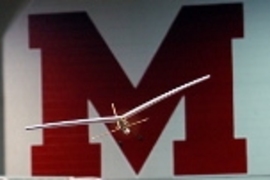 An egg-bearing model airplane soars in Johnson Athletic Center during aero/astro's unified aerial competition.