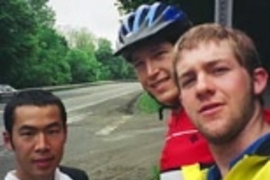MIT students and cross-country cyclists Taku Iida, Greg Mahowald and Kyle Rattray cross the Massachusetts-New York border.