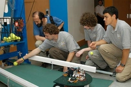Vermont's Essex High School team demonstrates its robotic tennis ball retriever, Roboscooper, one of the inventions presented at the InvenTeams Odyssey held at MIT. Ben Rome places a ball prior to the demonstration while Alex Franz looks on at right.