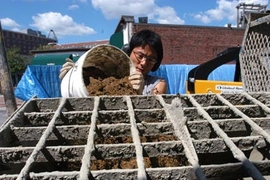 A team of MIT architecture students built a wall behind the MIT Museum by following an ancient construction technique known as "rammed earth." Here, graduate student Shuji Suzumori prepares the mixture of Boston Blue Clay, sand and gravel that was used to build the wall.