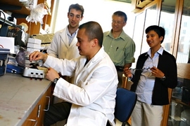 Andy Wijaya, an MIT graduate student in chemical engineering, prepares a gold nanorod solution for pump-probe spectroscopy with (standing, left to right) postdoc Aaron Schmidt and professors Gang Chen and Kimberly Hamad-Schifferli observing.