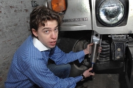 Zack Anderson , senior in elecrical engineering and computer sciences, holds a GenShock prototype up to a Humvee coil spring where it is installed.