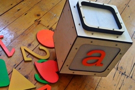 The Alphabot, a prototype robot that appears to move seamlessly between the real world and an on-screen virtual world, is designed to resemble a child's alphabet block.