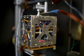 A magnetically levitated small satellite inside a vacuum chamber simulates space-like conditions to test the performance of mini ion thrusters in the laboratory.