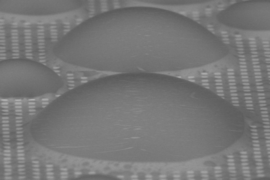 On a surface patterned with tiny pillars (white squares), and with a coating of a lubricant liquid that fills the spaces between the pillars, dome-shaped droplets of water condense but remain free to move quickly across the surface, unlike on conventional flat surfaces or ones with just the patterning, where they tend to stay stuck in place. The new surface treatment could provide a significant bo...