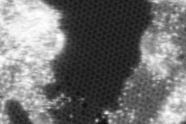 Another high-resolution scanning transmission electron microscope image taken at Oak Ridge National Laboratory showing a small hole in the graphene (small black region slightly below the center). The image is 8 nm by 8 nm, meaning that the hole is 0.5 nm in diameter. In this image the honeycomb structure of graphene lattice is clearly seen.