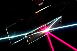 In this photo of the angular-selective sample (the rectangular region), a beam of white light passes through as if the sample was transparent glass. The red beam, coming in at a different angle, is reflected away, as if the sample was a mirror. The other lines are reflections of the beams. (This setup is immersed in liquid filled with light-scattering ­particles to make the rays visible).