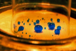 Tiny droplets of water, colored blue, are suspended in water on top of a membrane developed by the MIT team. Thanks to the membrane’s tiny pores, with a special coating that attracts water and repels oil, the droplets shrink as they pass through the membrane, ultimately leaving just pure oil behind. A similar membrane with a different coating can do the reverse, allowing oil droplets to pass whi...