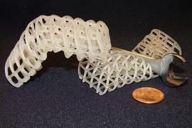 Two 3D-printed soft, flexible scaffolds: the one on the left is maintained in a rigid, bent position via a cooled, rigid wax coating, while the one on the right is uncoated and remains compliant (here, it collapses under a wrench).

