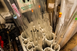 Different kinds of low-cost silicon dioxide tubes and rods sit in the lab. Researchers experimented by filling these tubes with a variety of metals to make a preform. When they tried aluminum, they found unexpected results.