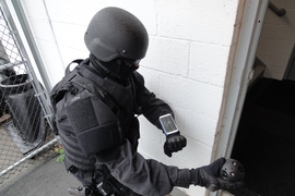 A police officer prepares to throw the Explorer into an unseen stairwell. The camera will then immediately send images of the area back to the smartphone on the officer's wrist. 
