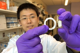 Shiyi Zhang, a postdoc at the Koch Institute and the paper’s lead author, holds a ring-shaped device prototype (left), which can be folded into a swallowable capsule (right) for easy and safe oral delivery.
