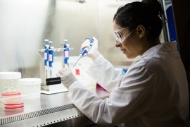 Mariana Matus working in a lab, wearing white lab coat and goggles