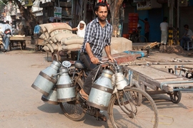 A man delivers pails of fresh milk to customers in rural India. 