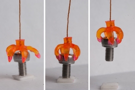 In this series, a 3-D printed multimaterial shape-memory minigripper, consisting of shape-memory hinges and adaptive touching tips, grasps a cap screw.
