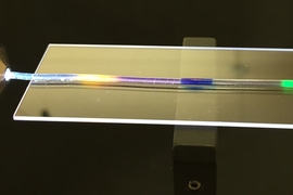 MIT researchers have developed a stretchy optical fiber in which they have injected multiple organic dyes (yellow, blue, and green regions). In addition to lighting up, the dyes act as a strain sensor, enabling researchers to quantify where and by how much a fiber has been stretched. 
