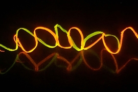 A photograph shows regenerated helical silk fibers colored by Rhodamine dyes, under UV light.
