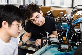 Sang-won Leigh, left, who earned a PhD from the MIT Media Lab in 2018, works with second-year student Ethan Nevidomsky, an electrical engineering and computer science major, on ArtMatr’s oil-based printing system during the Computing Connections Challenges.