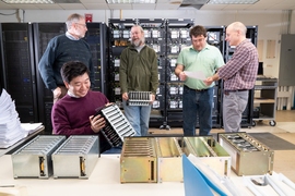 From left: Colin Lonsdale, the director of Haystack and vice-chair of the EHT Directing Board of Partners; Kazunori Akiyama (seated), coordinator of the EHT Imaging Working Group; Geoff Crew, co-lead of the Event Horizon Telescope Consortium (EHTC), holding a Haystack-developed data recorder; Vincent Fish, co-lead of the EHTC; and Michael Titus, technical correlation staff.
