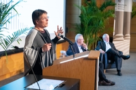 Susanne Moser, director of Susanne Moser Research and Consulting, addresses MIT’s second Symposium on Climate Change. In the background are Andrew Steer, president and CEO of the World Resources Institute, and Richard Schmalensee, the Howard W. Johnson Professor of Management and Professor of Economics Emeritus at the MIT Sloan School of Management, who moderated the panel discussions.