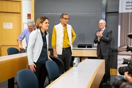 Esther Duflo and Abhijit Banerjee are photographed as the MIT press conference concludes. President L. Rafael Reif is also pictured.